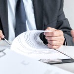 Steuerberatung Reindl, Hergenröder und Partner - Mann hält Stift in der Hand und unterschreibt Papier.