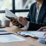 Steuerberatung Reindl, Hergenröder und Partner - Frau schreibt, mit einem Stift, etwas in ein Notizbuch