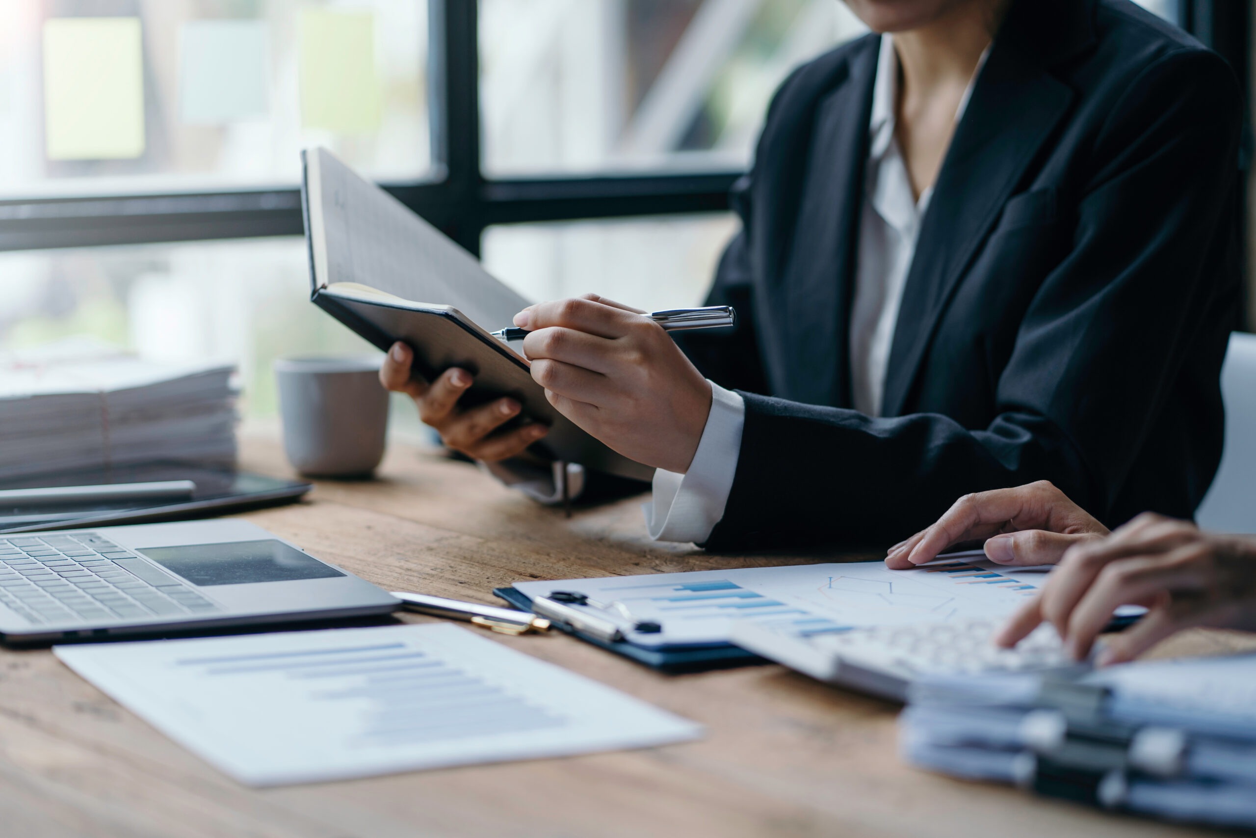 Steuerberatung Reindl, Hergenröder und Partner - Frau schreibt, mit einem Stift, etwas in ein Notizbuch