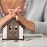 Steuerberatung Reindl, Hergenröder und Partner - Ältere Hände liegen auf einem kleinen Haus