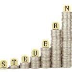 Steuerberatung Reindl, Hergenröder und Partner - Würfel mit Schriftzug Steuern auf Kleingeldstapeln