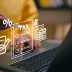 Steuerberatung Reindl, Hergenröder und Partner - Hand hat Stift in der Hand und zeigt auf Schriftzug TAX vor Computer.